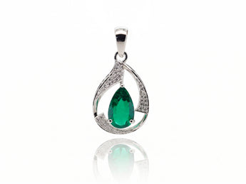A silver teardrop pendant featuring a central green emerald-cut gemstone and pavé-set clear stones along the curved sides, shown on a white background with a soft reflection below.