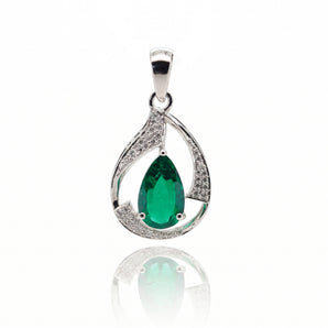 A silver teardrop pendant featuring a central green emerald-cut gemstone and pavé-set clear stones along the curved sides, shown on a white background with a soft reflection below.